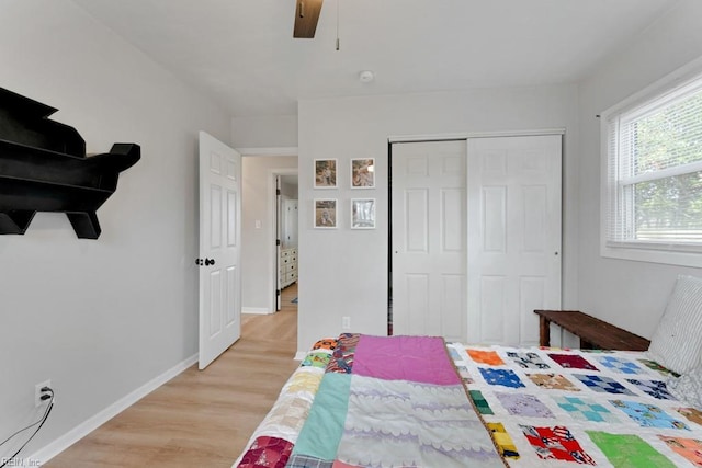 bedroom featuring ceiling fan, a closet, light wood-type flooring, and baseboards