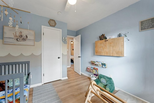 bedroom featuring ceiling fan, light wood-style flooring, and baseboards