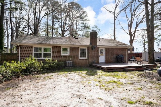 back of property with a chimney, fence, a wooden deck, central air condition unit, and brick siding