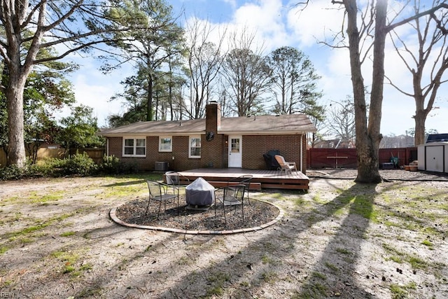 rear view of house with brick siding, fence, a deck, and a shed