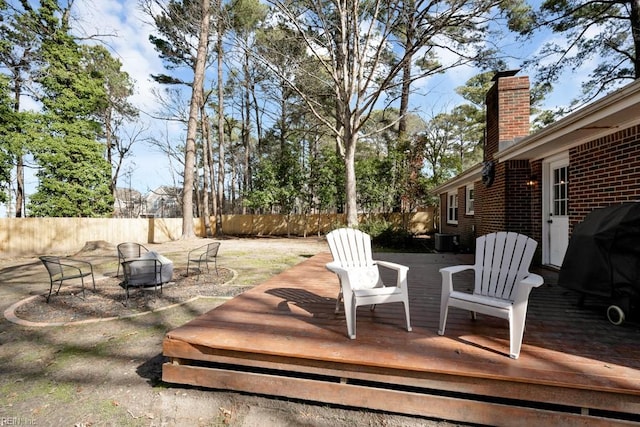 wooden deck featuring an outdoor fire pit, a grill, fence, and central AC unit