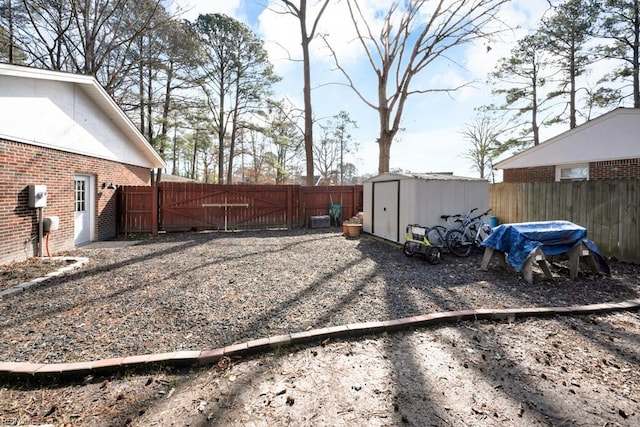 view of yard featuring a fenced backyard, a gate, a storage unit, and an outbuilding