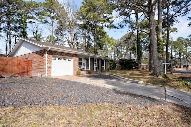 view of side of home with driveway, an attached garage, fence, and brick siding