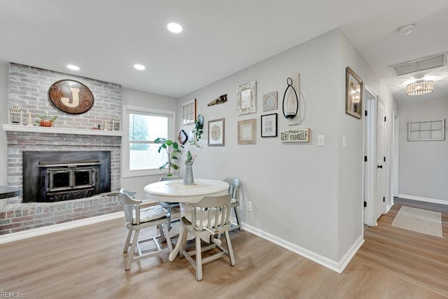 dining area with a fireplace, recessed lighting, attic access, light wood-type flooring, and baseboards