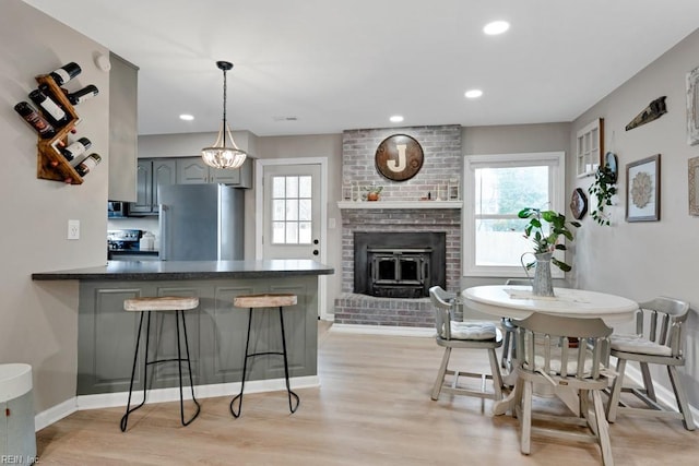 kitchen with a breakfast bar, decorative light fixtures, stainless steel appliances, gray cabinets, and a peninsula