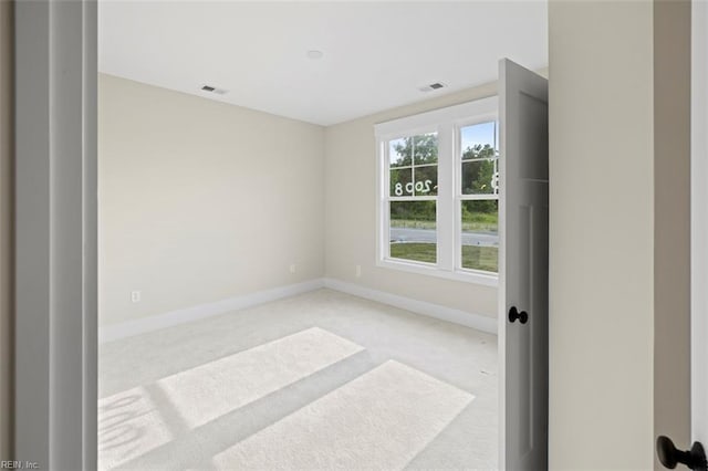 unfurnished room with light colored carpet, visible vents, and baseboards