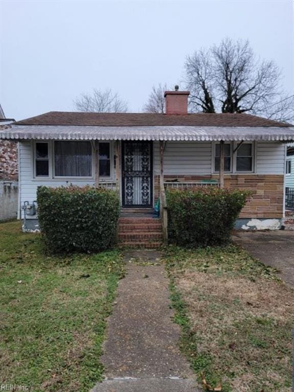 view of front facade featuring a front lawn and a chimney