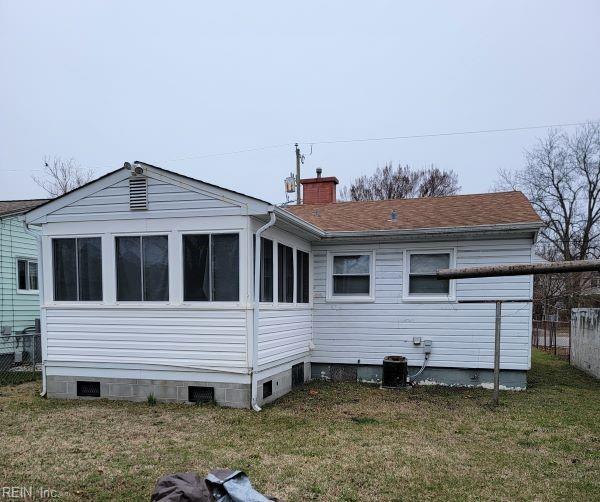 rear view of property featuring crawl space, a chimney, and a lawn