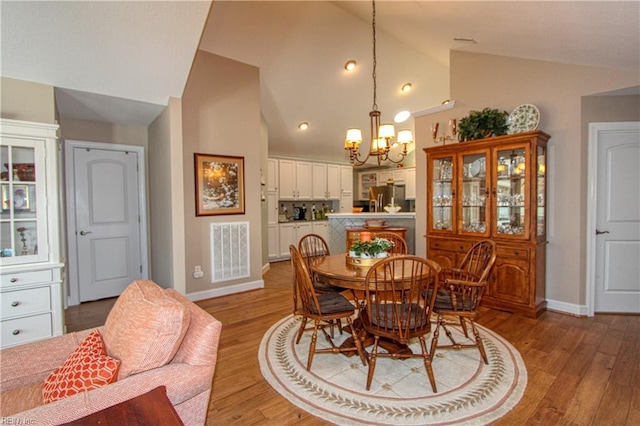 dining space featuring baseboards, light wood-style flooring, visible vents, and a notable chandelier