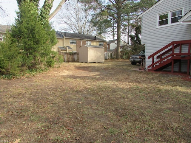 view of yard with a shed, stairway, an outdoor structure, and fence