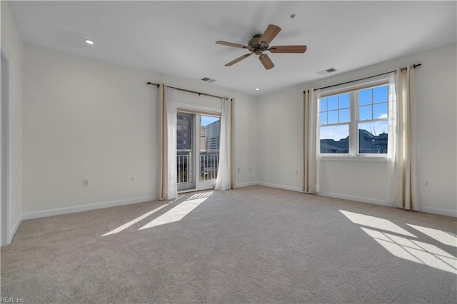 unfurnished room with plenty of natural light, visible vents, baseboards, and light colored carpet