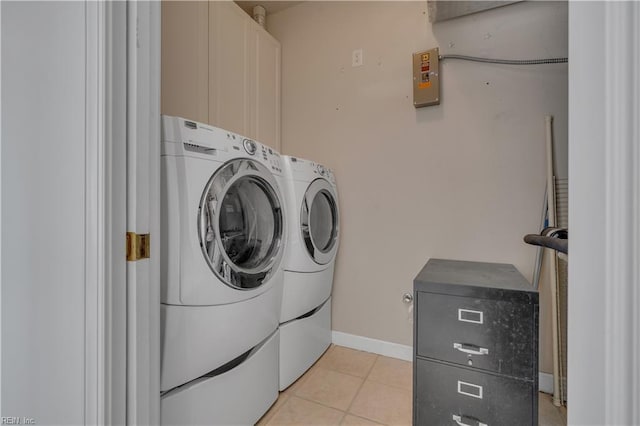 clothes washing area featuring washer and clothes dryer, light tile patterned flooring, cabinet space, and baseboards