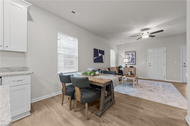 dining area with light wood-type flooring, visible vents, ceiling fan, and baseboards