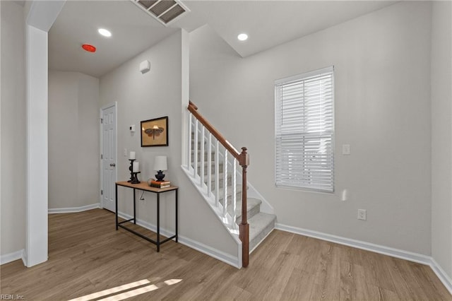 staircase featuring baseboards, visible vents, wood finished floors, and recessed lighting