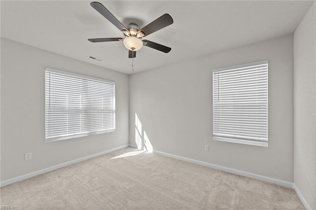 spare room with baseboards, visible vents, ceiling fan, and light colored carpet