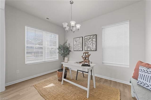 office space with a chandelier, light wood-style flooring, visible vents, and baseboards