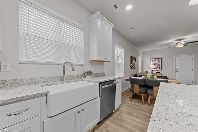 kitchen with a sink, visible vents, white cabinets, stainless steel dishwasher, and light stone countertops