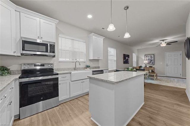 kitchen featuring stainless steel appliances, light wood finished floors, a sink, and white cabinetry