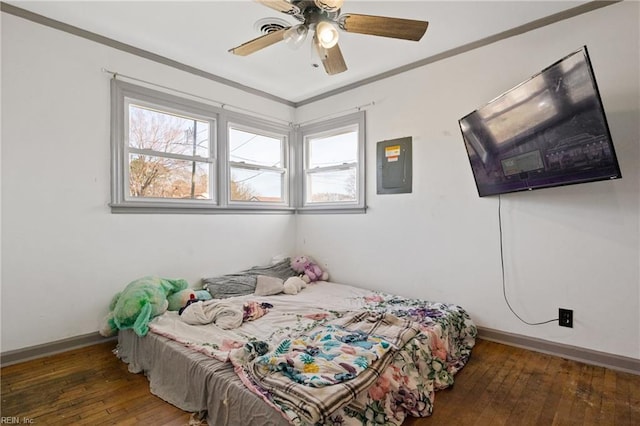 bedroom with dark wood-style floors, crown molding, a ceiling fan, electric panel, and baseboards