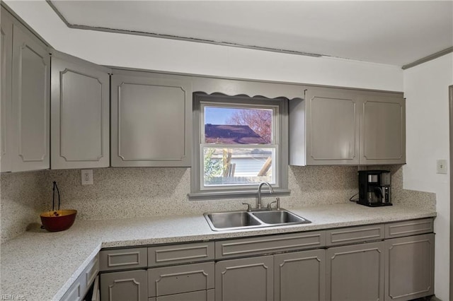 kitchen featuring light countertops, tasteful backsplash, gray cabinets, and a sink