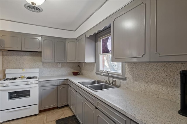 kitchen featuring gray cabinets, light countertops, visible vents, a sink, and white gas range oven