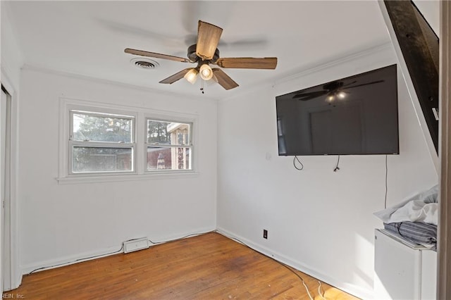 unfurnished room with ceiling fan, crown molding, visible vents, and wood finished floors