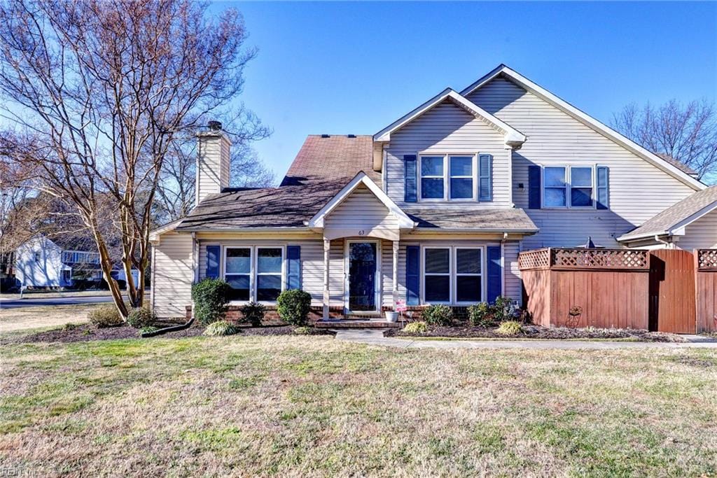 view of front of home featuring fence, a chimney, and a front lawn