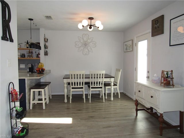 dining area featuring visible vents, a notable chandelier, baseboards, and wood finished floors