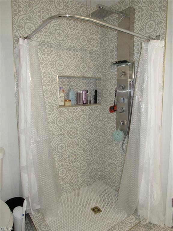 bathroom featuring a tile shower and toilet