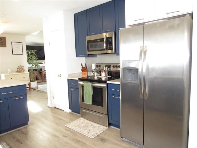 kitchen with stainless steel appliances, light countertops, and blue cabinetry