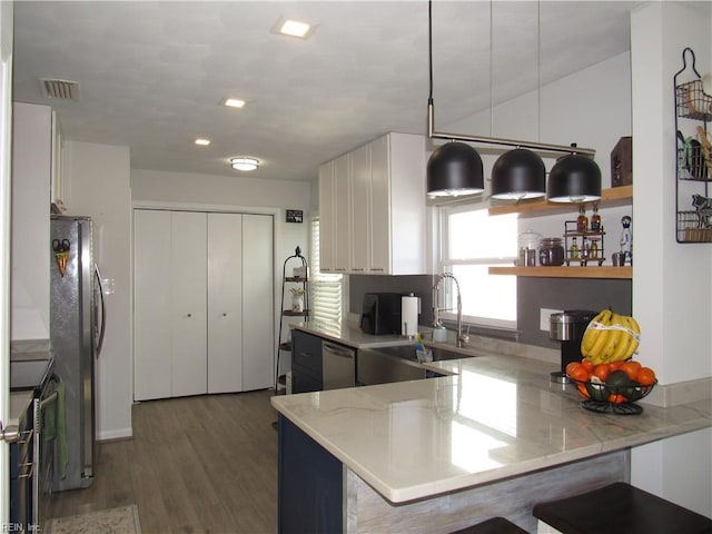 kitchen featuring a peninsula, a sink, visible vents, and white cabinets