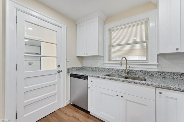 kitchen featuring white cabinets, light wood-style flooring, light stone countertops, stainless steel dishwasher, and a sink