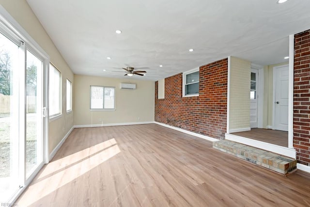 unfurnished room featuring recessed lighting, brick wall, baseboards, an AC wall unit, and light wood finished floors