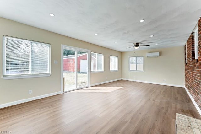 unfurnished living room with ceiling fan, recessed lighting, baseboards, light wood-type flooring, and a wall mounted air conditioner