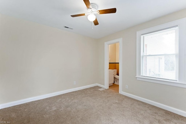 unfurnished bedroom with light carpet, a ceiling fan, visible vents, baseboards, and ensuite bath