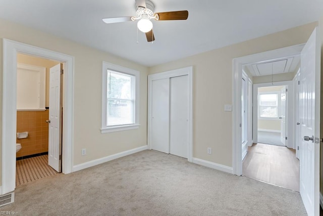 unfurnished bedroom featuring attic access, a closet, light carpet, and connected bathroom