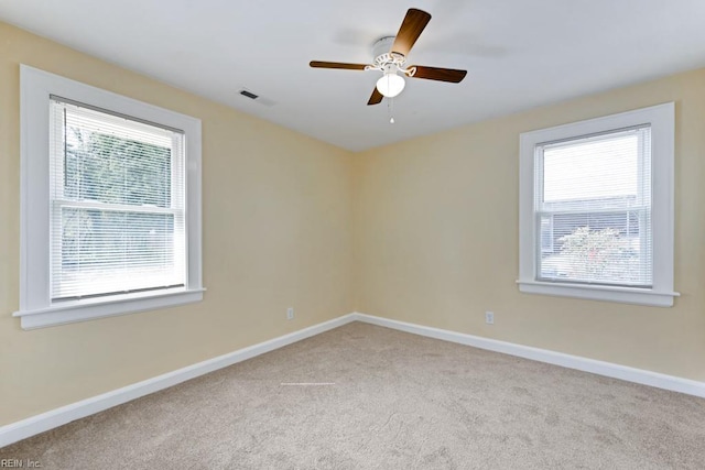 unfurnished room with light carpet, visible vents, baseboards, and a ceiling fan