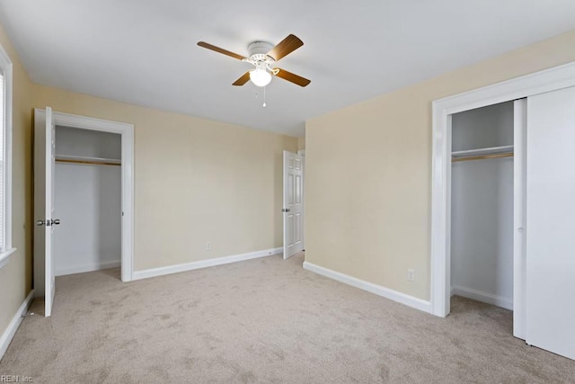 unfurnished bedroom with light carpet, baseboards, and multiple closets