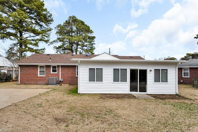 rear view of property with central air condition unit, a patio, a lawn, and brick siding