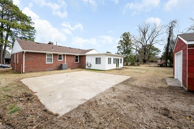 back of house with a patio, central air condition unit, brick siding, roof with shingles, and a chimney