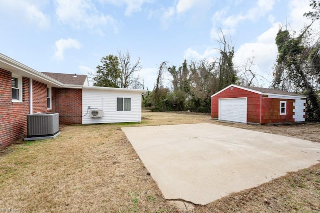 view of patio featuring an outbuilding, a detached garage, driveway, and central air condition unit