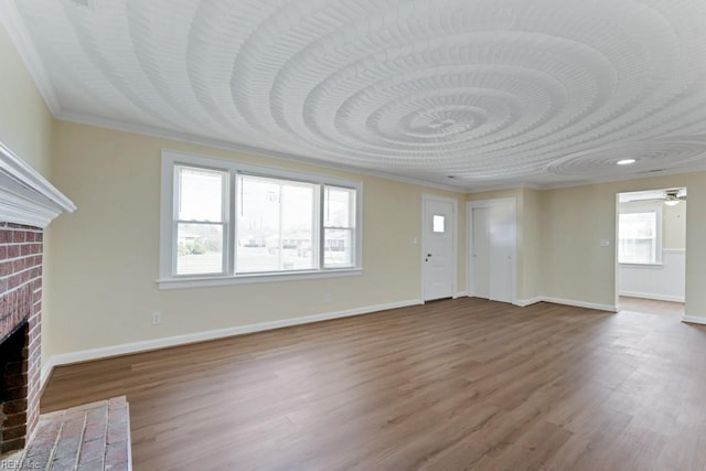 unfurnished living room featuring a brick fireplace, wood finished floors, and baseboards