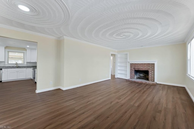 unfurnished living room featuring dark wood-style floors, built in shelves, a fireplace, crown molding, and baseboards