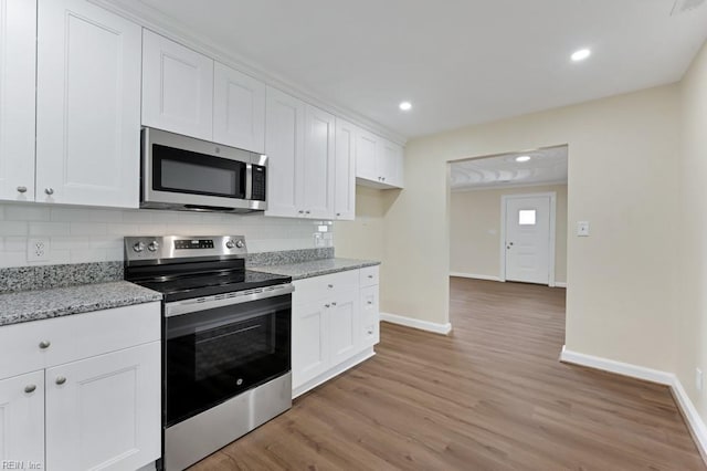 kitchen with decorative backsplash, light wood-style flooring, light stone countertops, stainless steel appliances, and white cabinetry