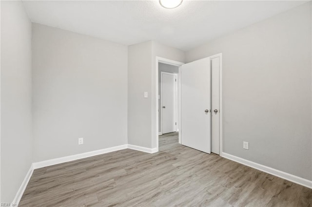 unfurnished room with light wood-style flooring and baseboards