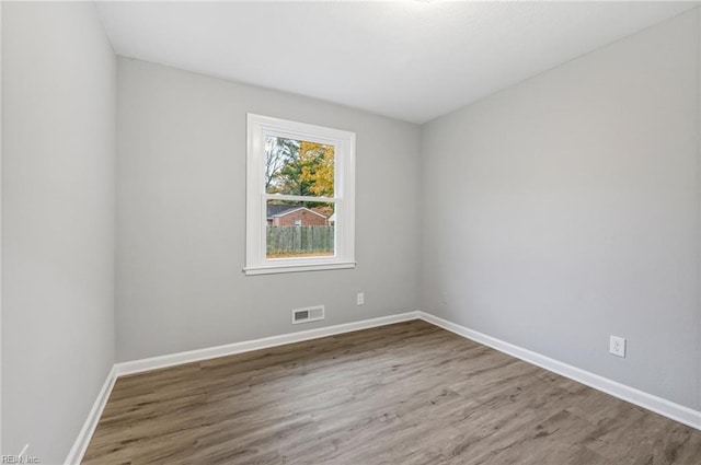 unfurnished room featuring wood finished floors, visible vents, and baseboards