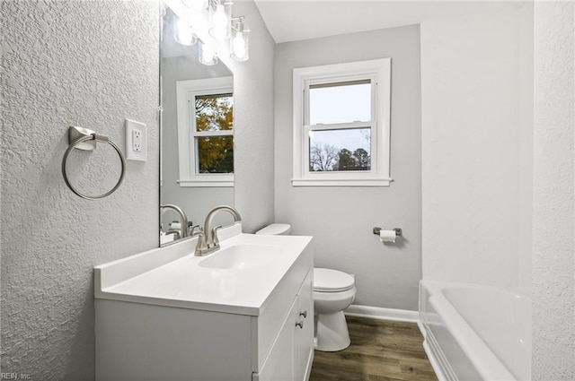 bathroom with baseboards, toilet, wood finished floors, a bathtub, and vanity