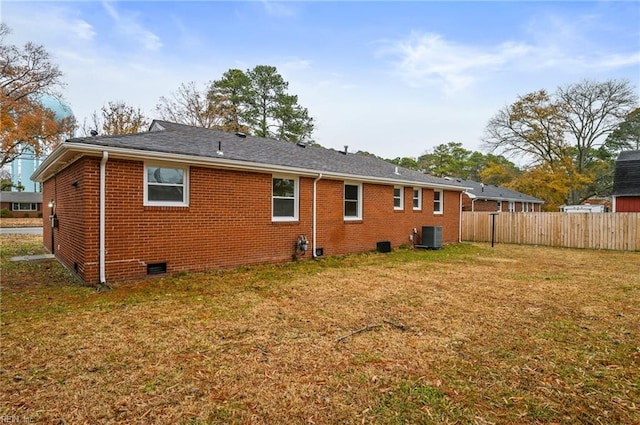 rear view of property with brick siding, a lawn, cooling unit, and fence