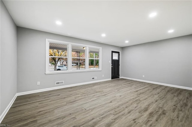 unfurnished room featuring baseboards, visible vents, wood finished floors, and recessed lighting