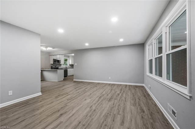 unfurnished living room featuring baseboards, visible vents, wood finished floors, and recessed lighting